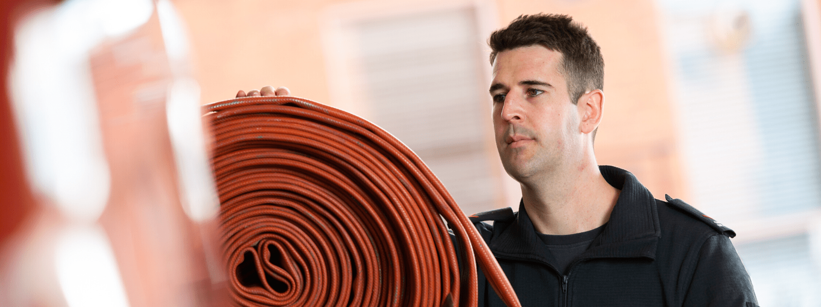 A firefighter inspecting a hose on a truck 