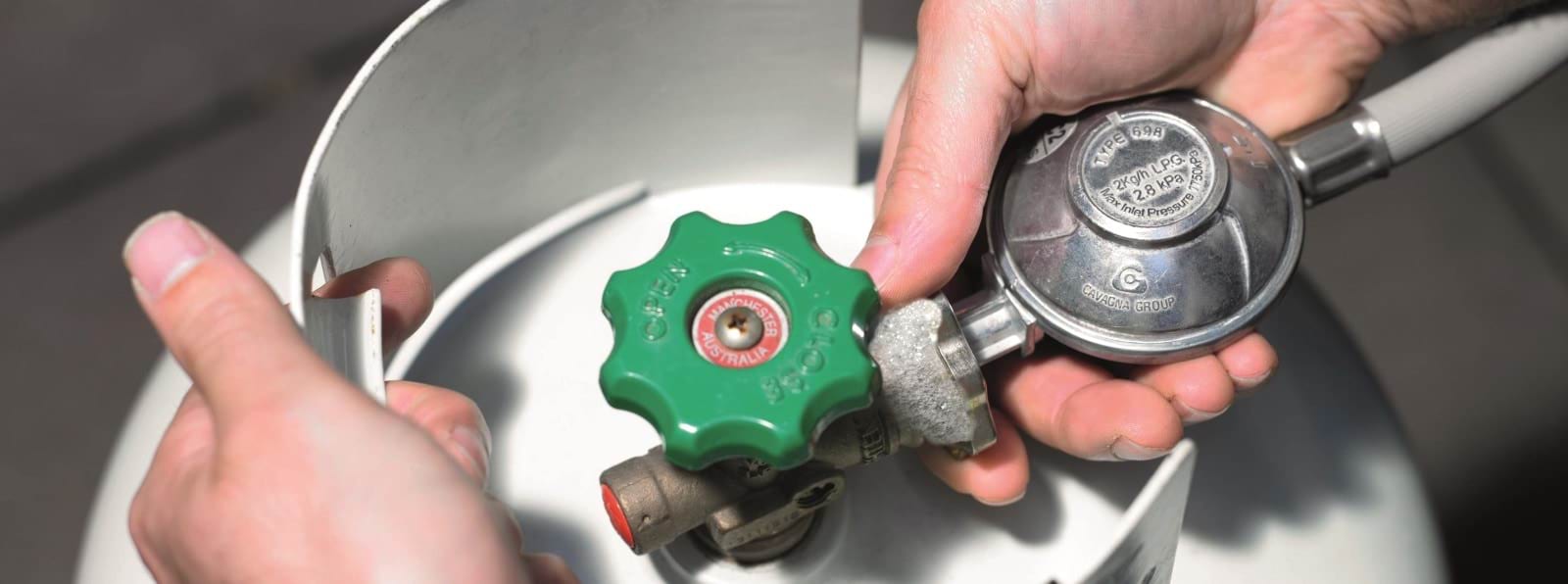 A person inspecting the barbecue hose connection, with bubbles forming